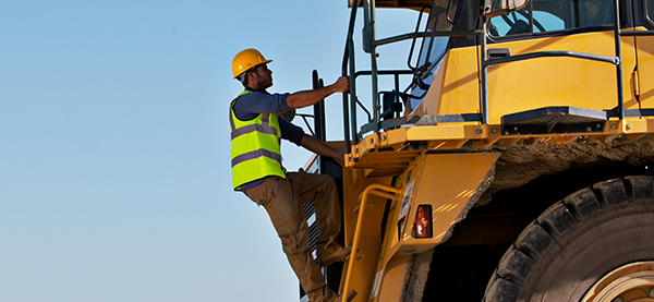 Construction worker climbing into a machine